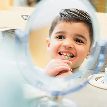 Young boy looking at his smile in a mirror