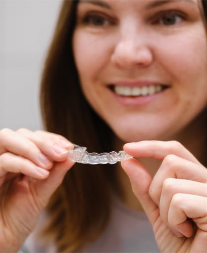 A woman holds a clear plastic toothbrush, showcasing its transparent design and modern aesthetic.