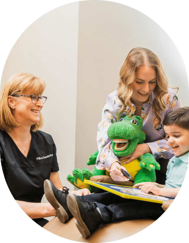 A woman and two children are seated at a table, with a stuffed animal placed in front of them.