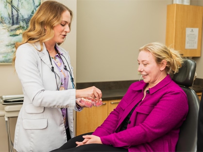 A doctor checks a woman's blood pressure during a routine medical examination in a clinical setting.