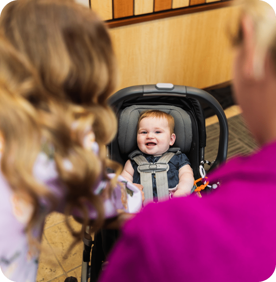 A woman gently pushes a stroller, cradling a baby, showcasing a tender moment of motherhood in a serene setting.