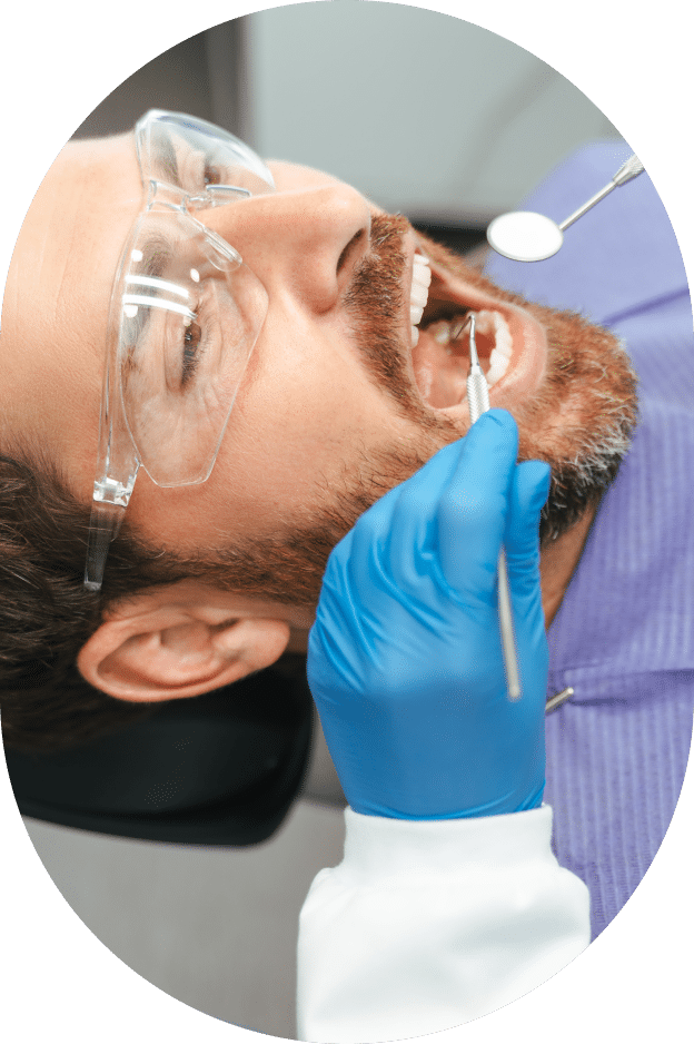 A man seated in a dental chair, wearing a blue glove on his hand, prepared for a dental examination.