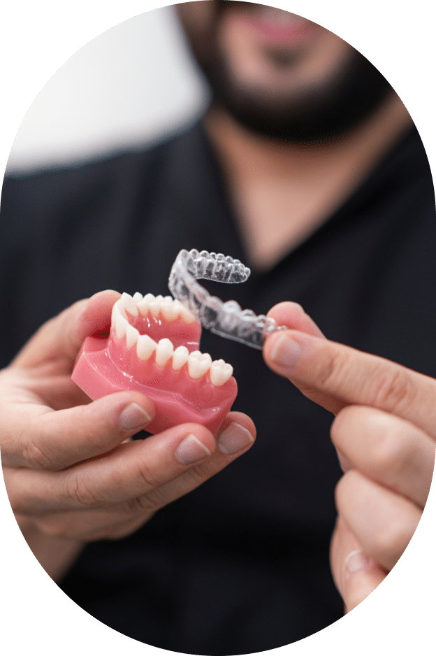 A man displays a tooth with an implant in his hand, showcasing dental restoration and oral health.