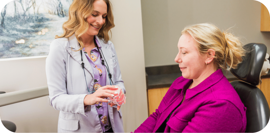 A woman consults with a doctor while seated in a chair, engaged in a discussion about her health.