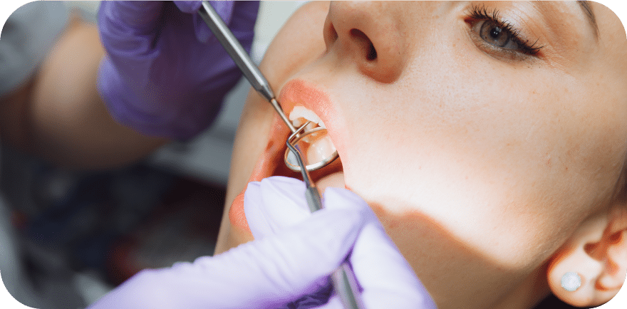 A woman receiving a dental cleaning from a dentist in a clinical setting.