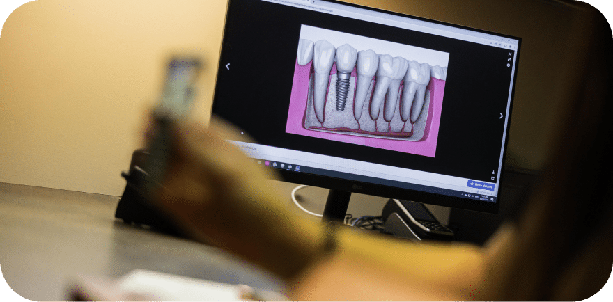 A person examines a dental image on a computer screen, focusing intently on the details displayed.