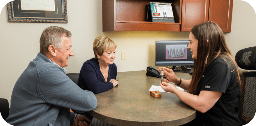 A woman and two men engaged in conversation while seated at a table, sharing ideas and enjoying each other's company.