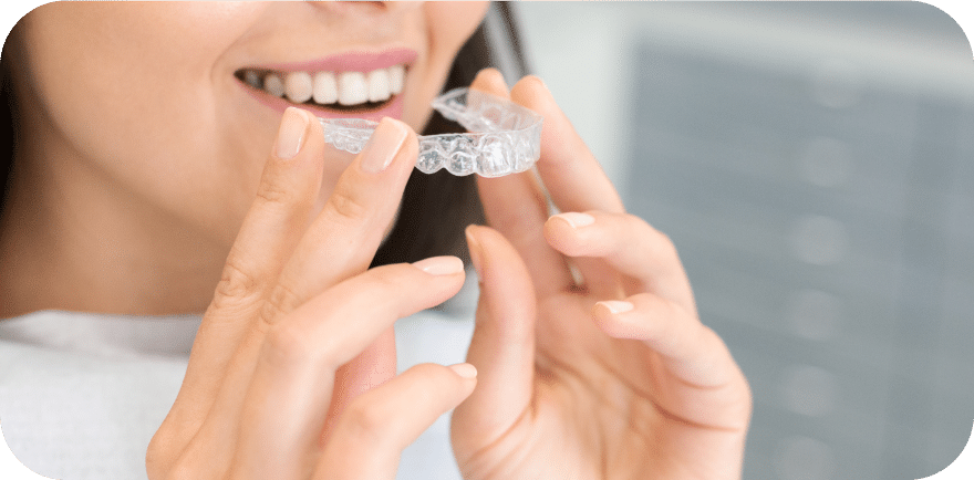 A woman using an oral care device while holding her teeth, emphasizing dental hygiene and personal care.