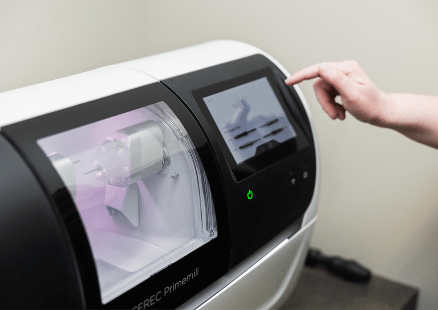 A person gestures towards a machine linked to a computer, indicating its functionality or operation