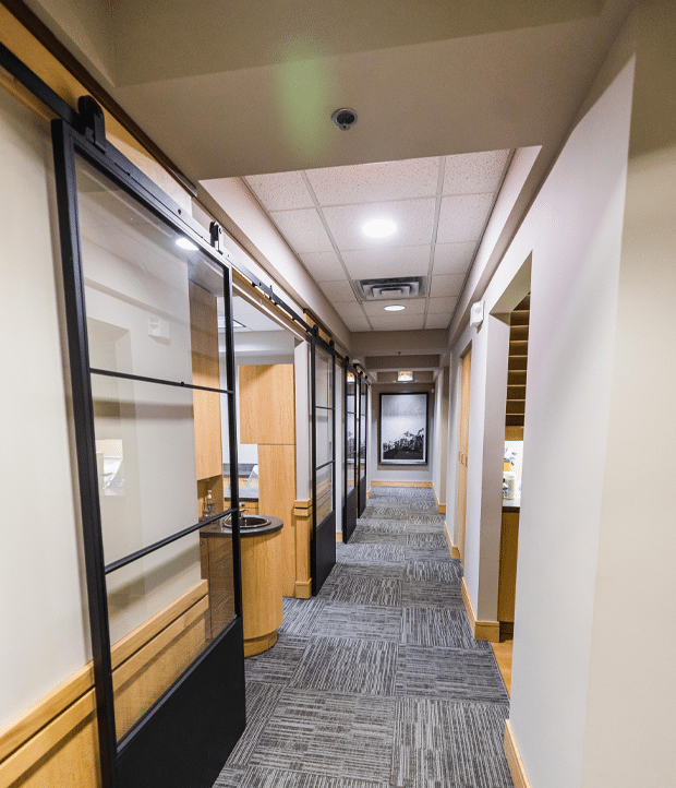 A hallway featuring glass doors and a desk, creating a modern and open atmosphere