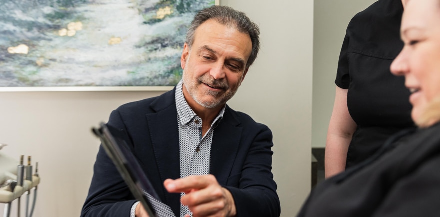 A man and woman in a dental office reviewing information on a tablet together