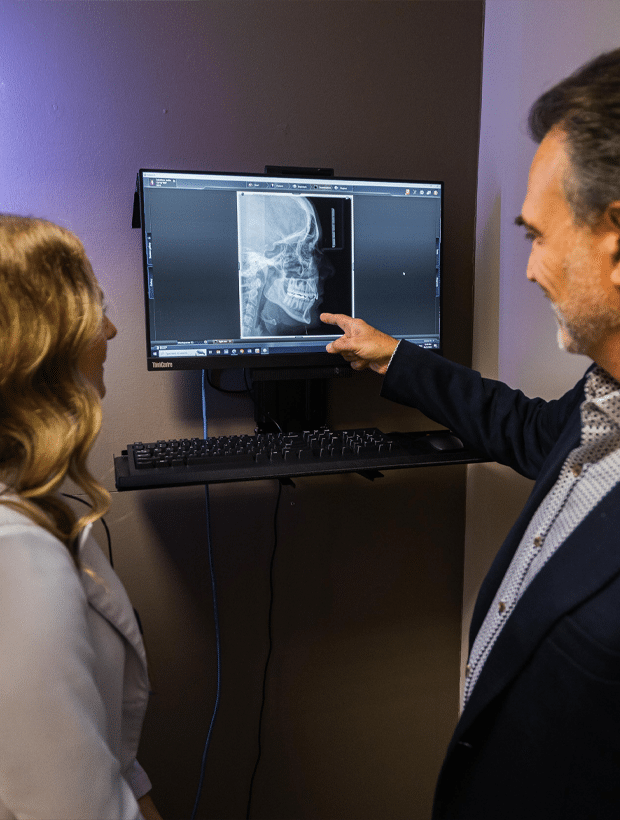 A man and woman examining an X-ray displayed on a computer screen, engaged in a discussion about the results