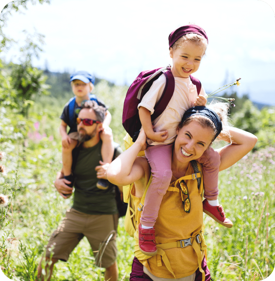 A family enjoys a scenic hike together in the mountains, surrounded by lush greenery and breathtaking views.