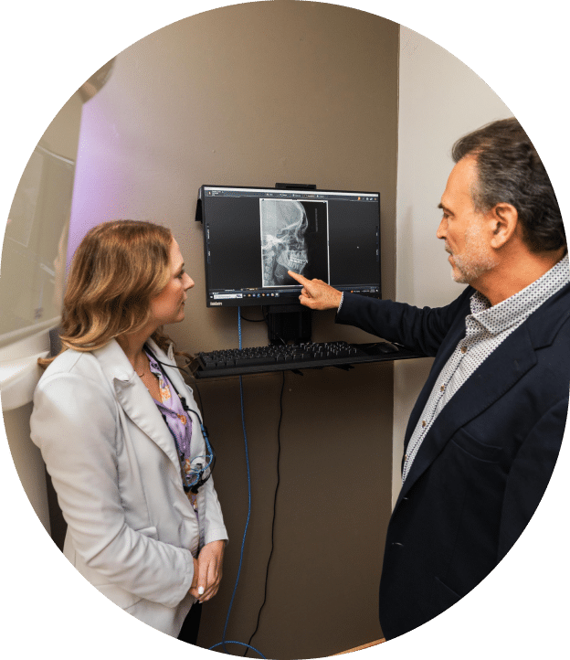 A man and woman examine an X-ray displayed on a monitor, discussing the details of the image