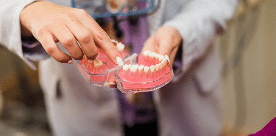 A person holds a toothbrush and a tooth, symbolizing dental hygiene and oral care practices