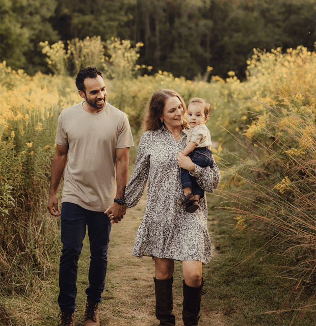 A joyful family gathered in a sunny field, smiling and posing for a memorable photo together